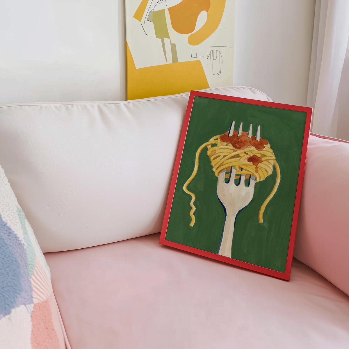 Spaghetti twirl print shown in a red frame leaning on a blush pink sofa