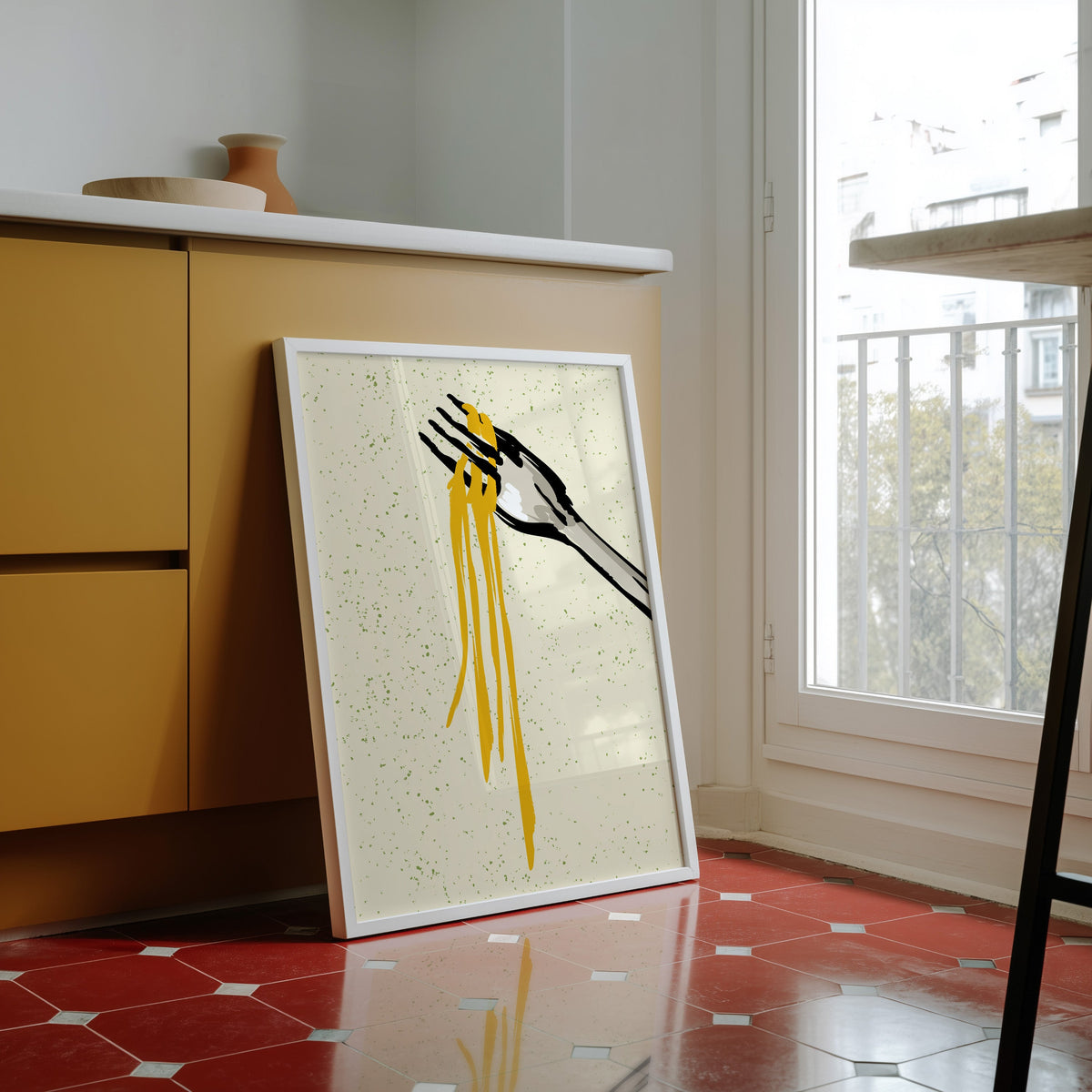 Spaghetti fork print in a white frame against yellow cabinets on a red tiled floor