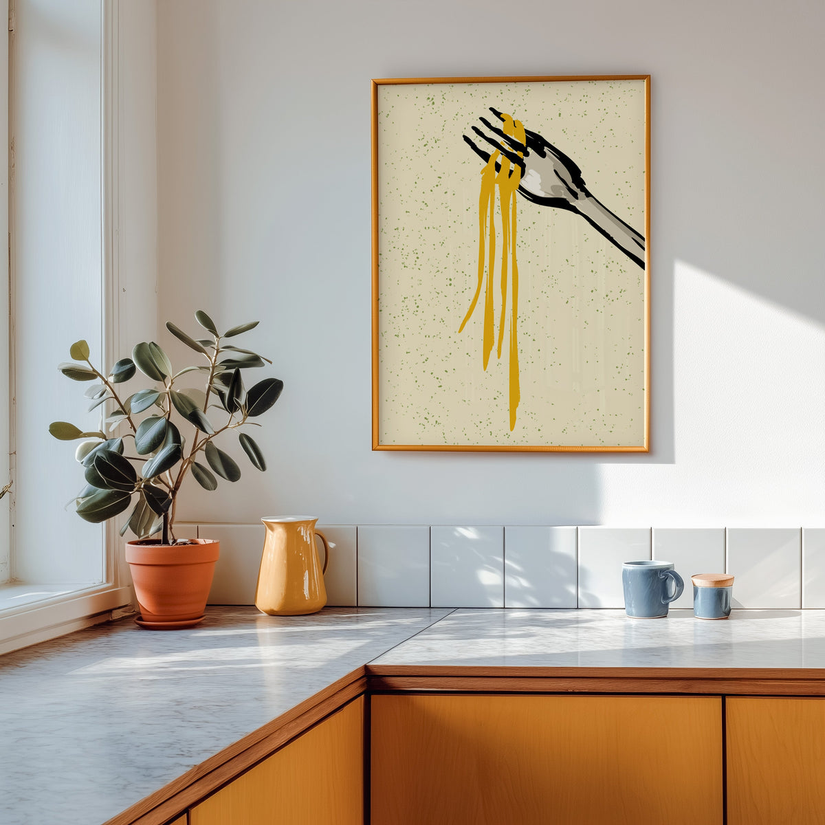 Spaghetti fork print shown in a gold frame above a marble counter with a yellow ceramic jug