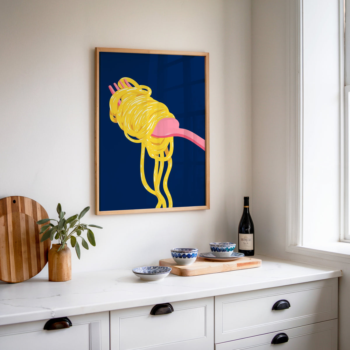 Spaghetti navy print in an oak frame above a white sideboard with a bottle of wine