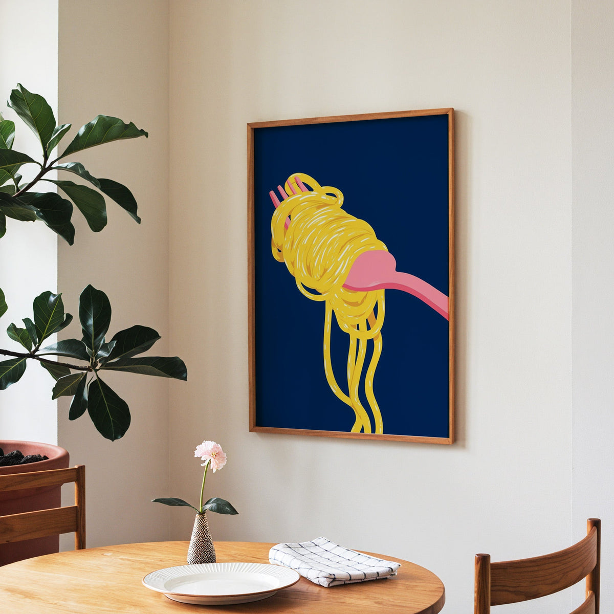 Spaghetti navy print in a walnut frame above a round table beside a fiddle-leaf fig