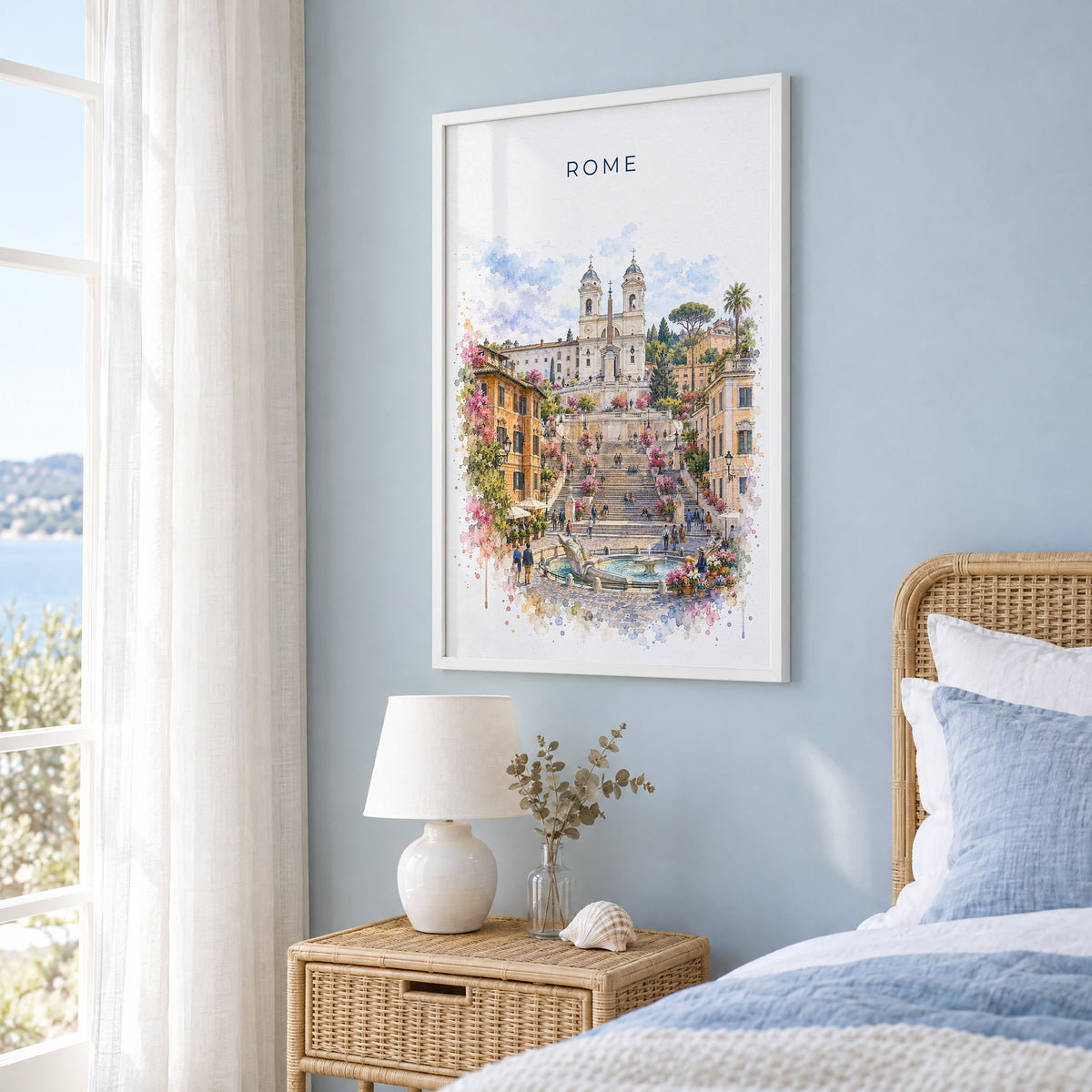 Spanish Steps watercolor print in a white frame on a pale blue wall beside a rattan bed in a coastal bedroom