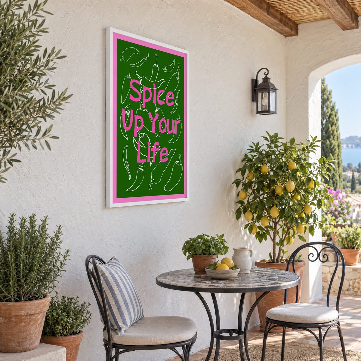Spice Up Your Life green chilli print in a white frame on a sunny patio wall beside a potted lemon tree
