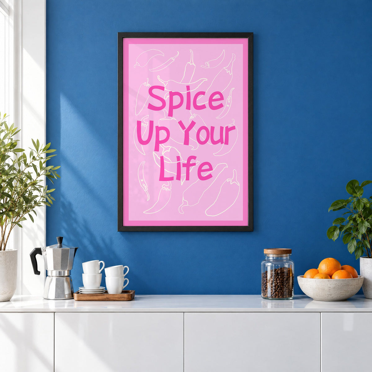 Spice Up Your Life pink chilli print in a black frame on a cobalt blue wall above a coffee station