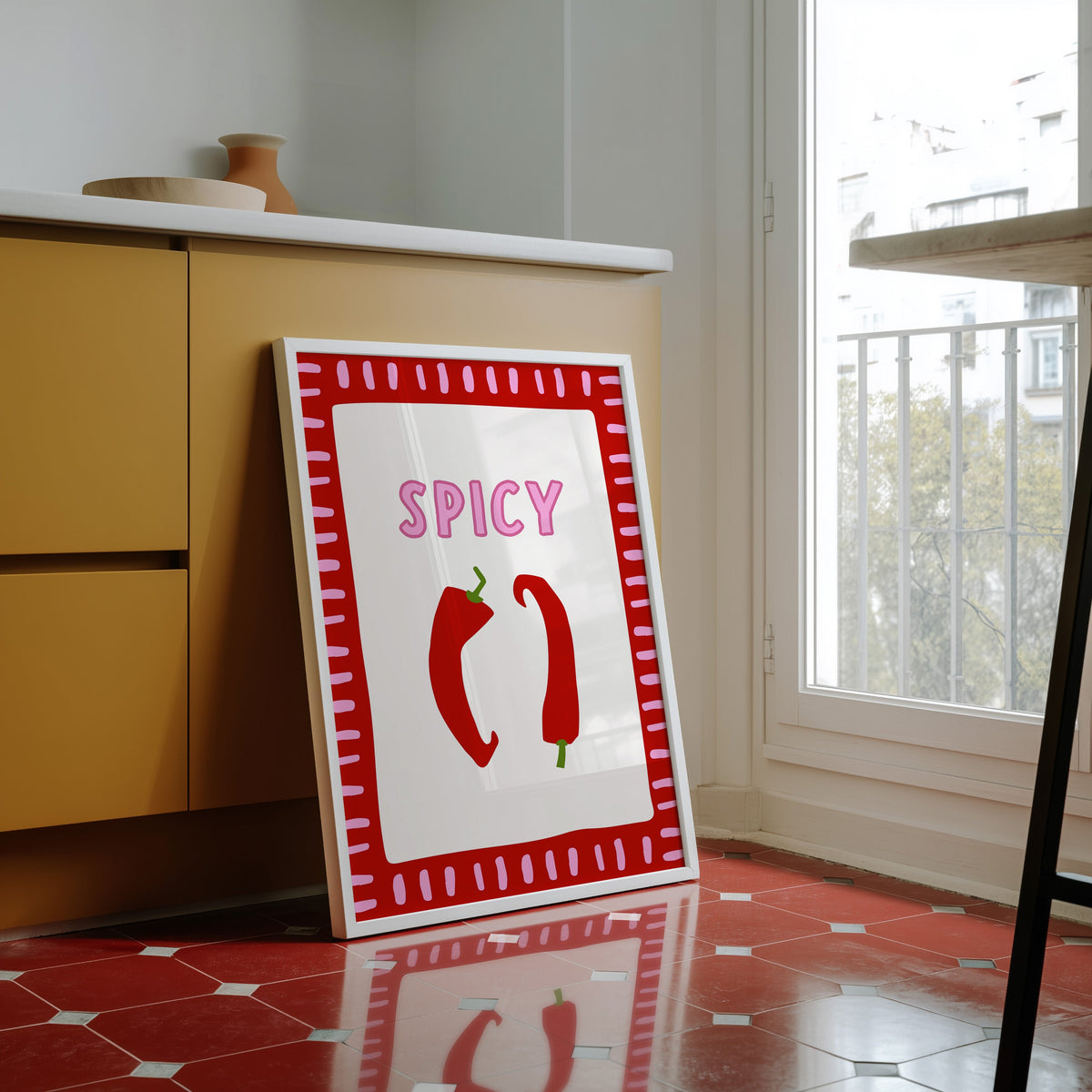 Spicy chilli print in a white frame against yellow cabinets on a red tiled floor