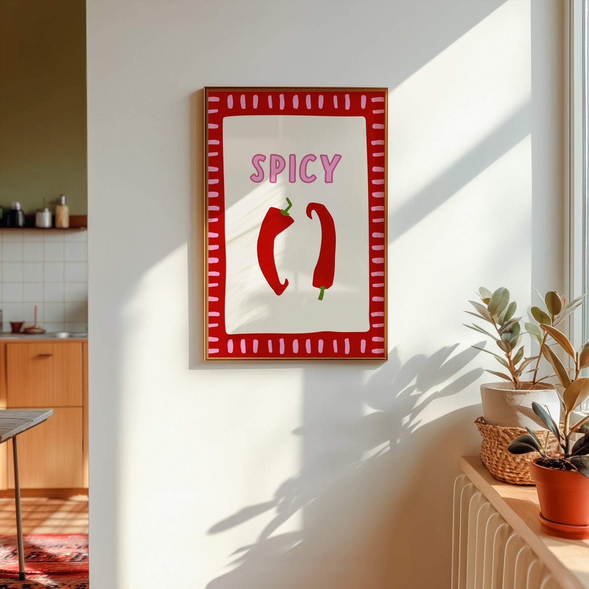 Spicy chilli print shown in a gold frame in sunlight with plants and a kitchen beyond