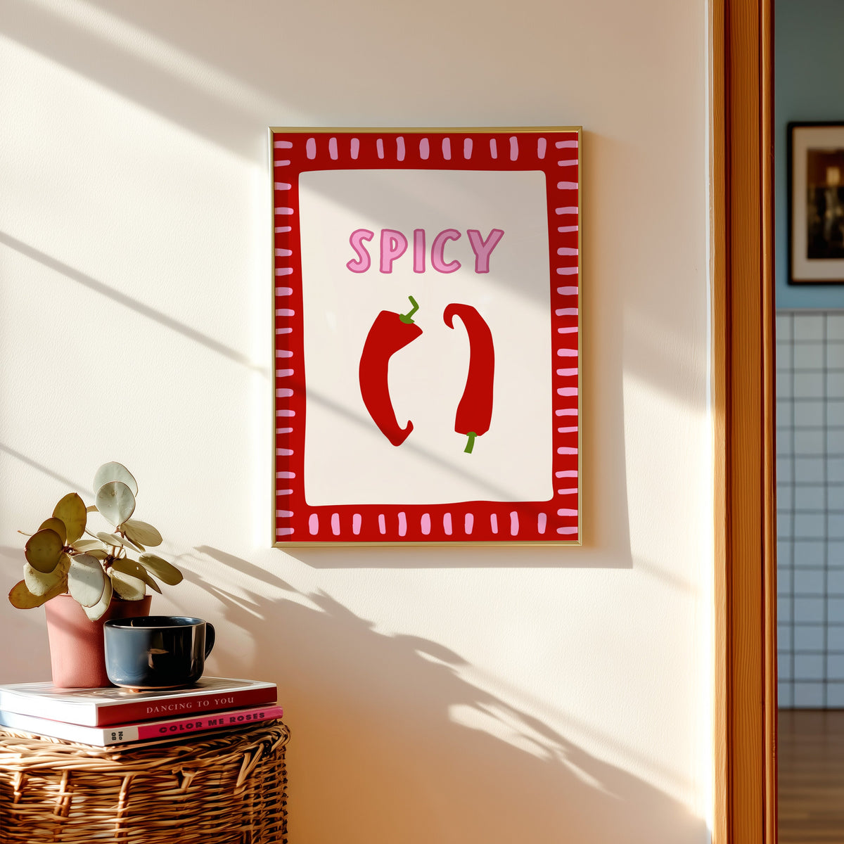Spicy chilli print shown in a gold frame above a basket of books and a pilea plant