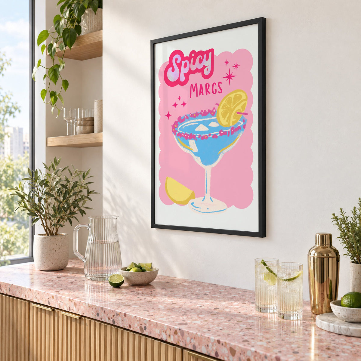 Spicy Margs blue margarita print in a black frame above a pink terrazzo cocktail counter with limes, seen at an angle