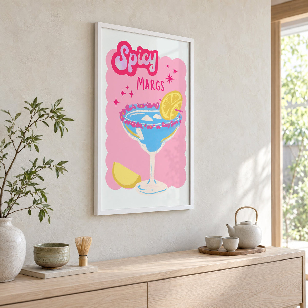 Spicy Margs blue margarita print in a white frame above a pale wood console with a matcha tea set