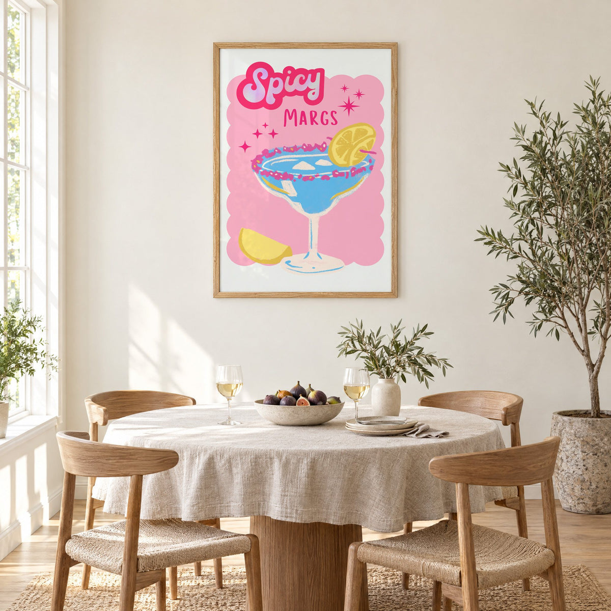 Spicy Margs blue margarita print in an oak frame above a round linen-covered dining table with figs and wine