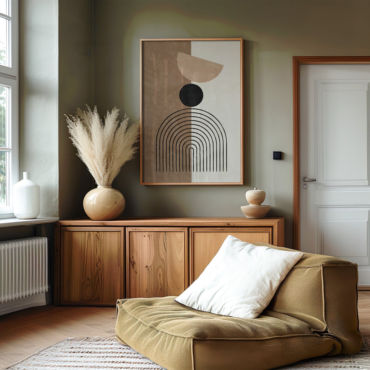 Split brown and cream line arch print in an oak frame on an olive green wall above a wood sideboard with pampas