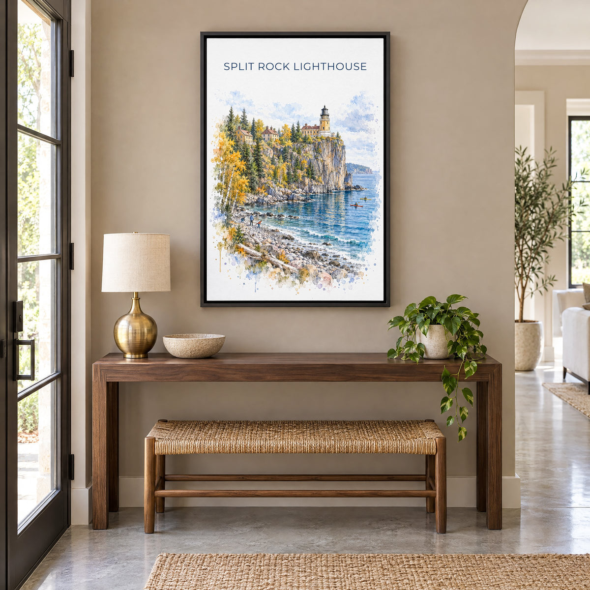 Split Rock Lighthouse watercolor print as a black floater canvas above a walnut console and woven bench in an entryway