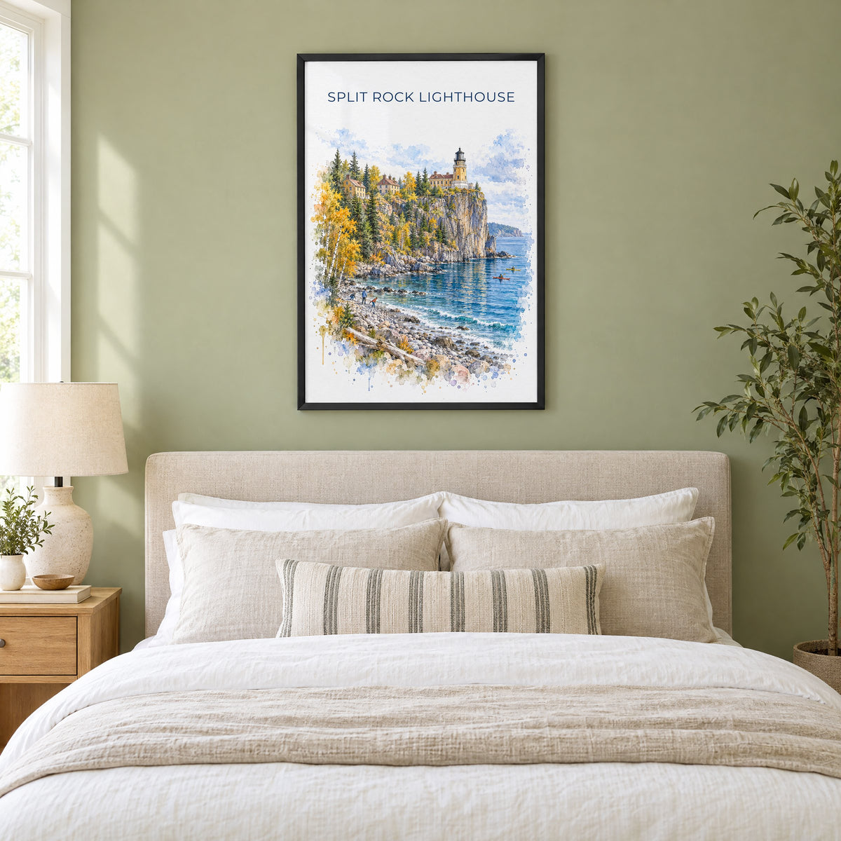 Split Rock Lighthouse watercolor print in a black frame above an upholstered headboard in a sage green bedroom