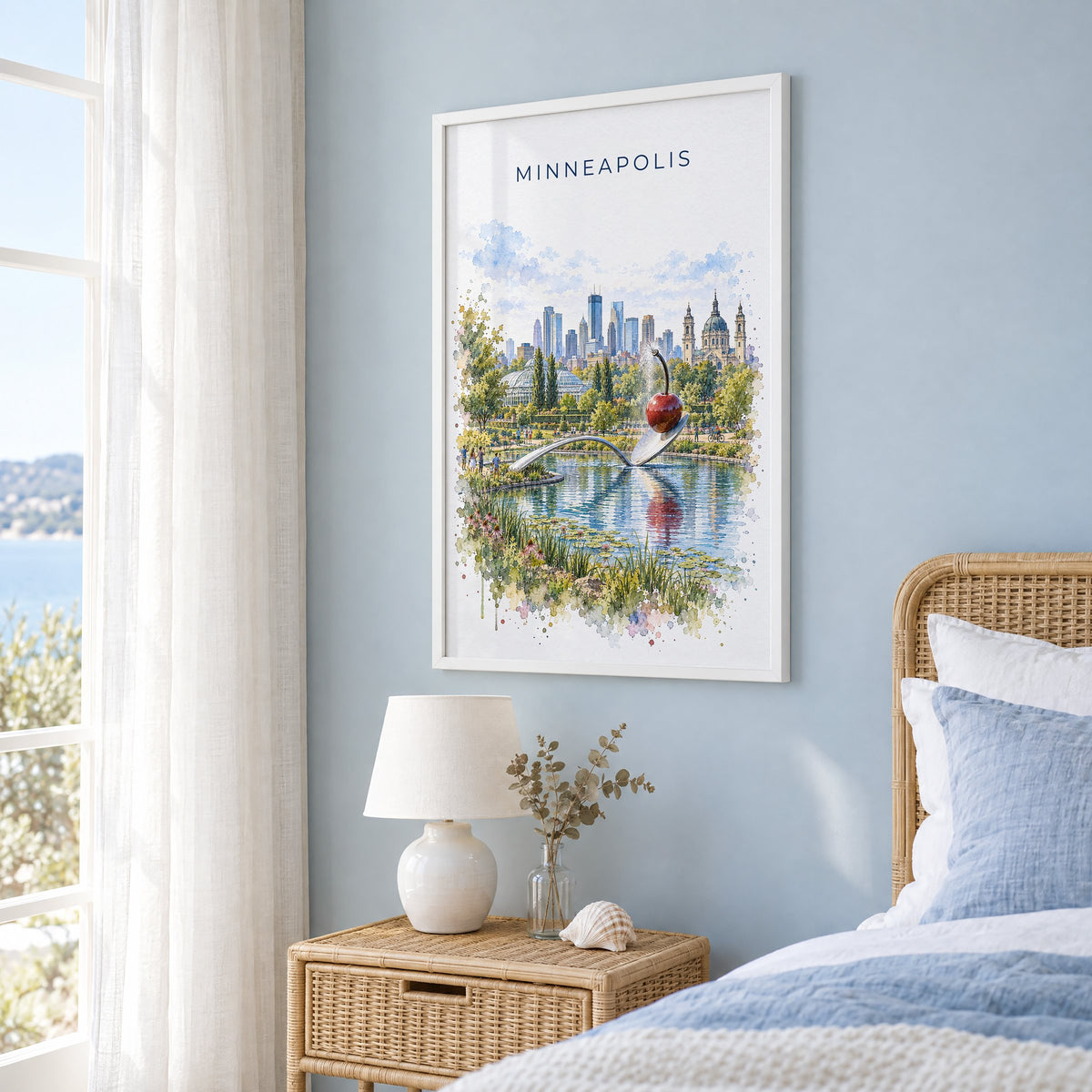 Spoonbridge and Cherry watercolor print in a white frame on a pale blue wall beside a rattan bed in a coastal bedroom