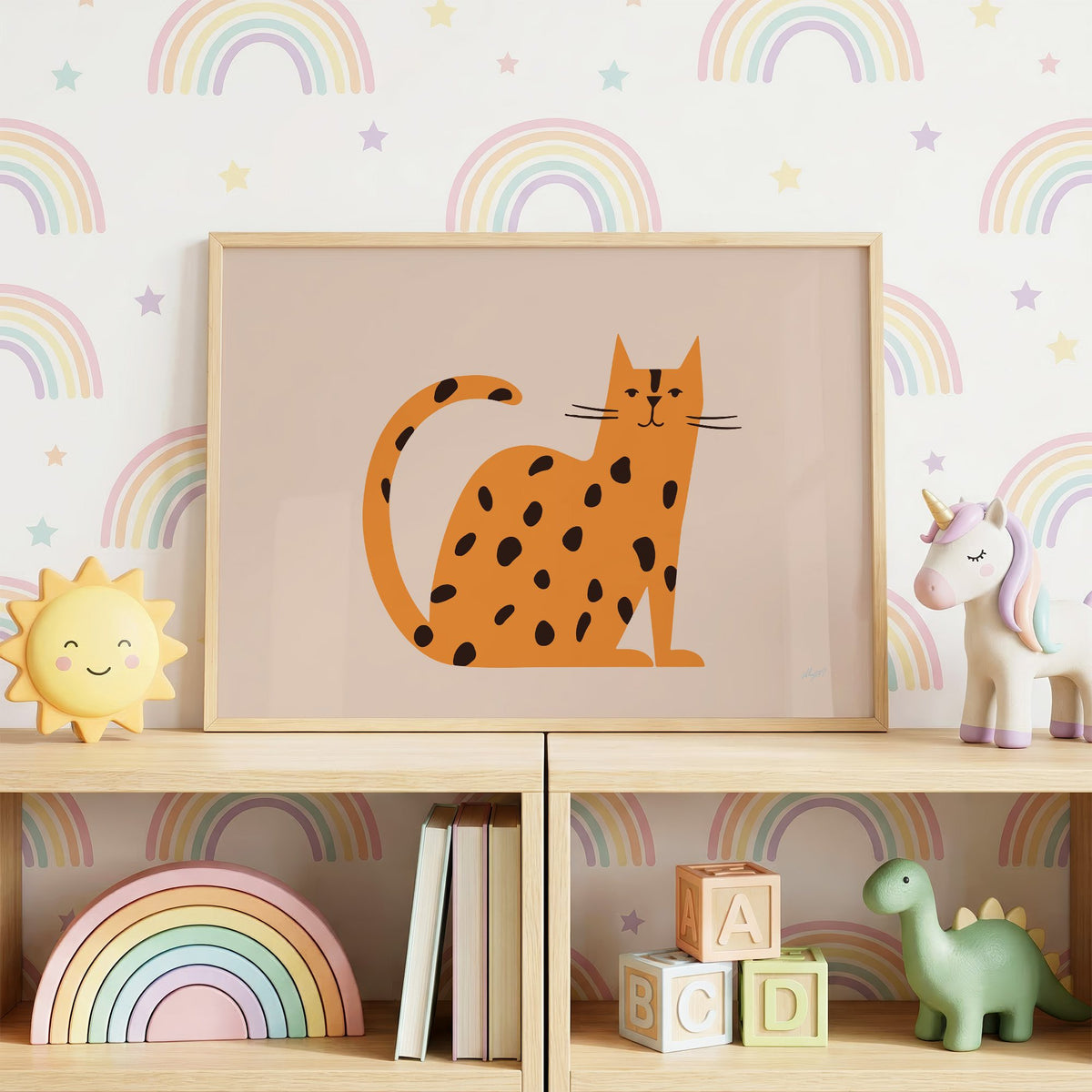 Minimal orange spotted cat nursery print in an oak frame on a toy shelf against rainbow wallpaper