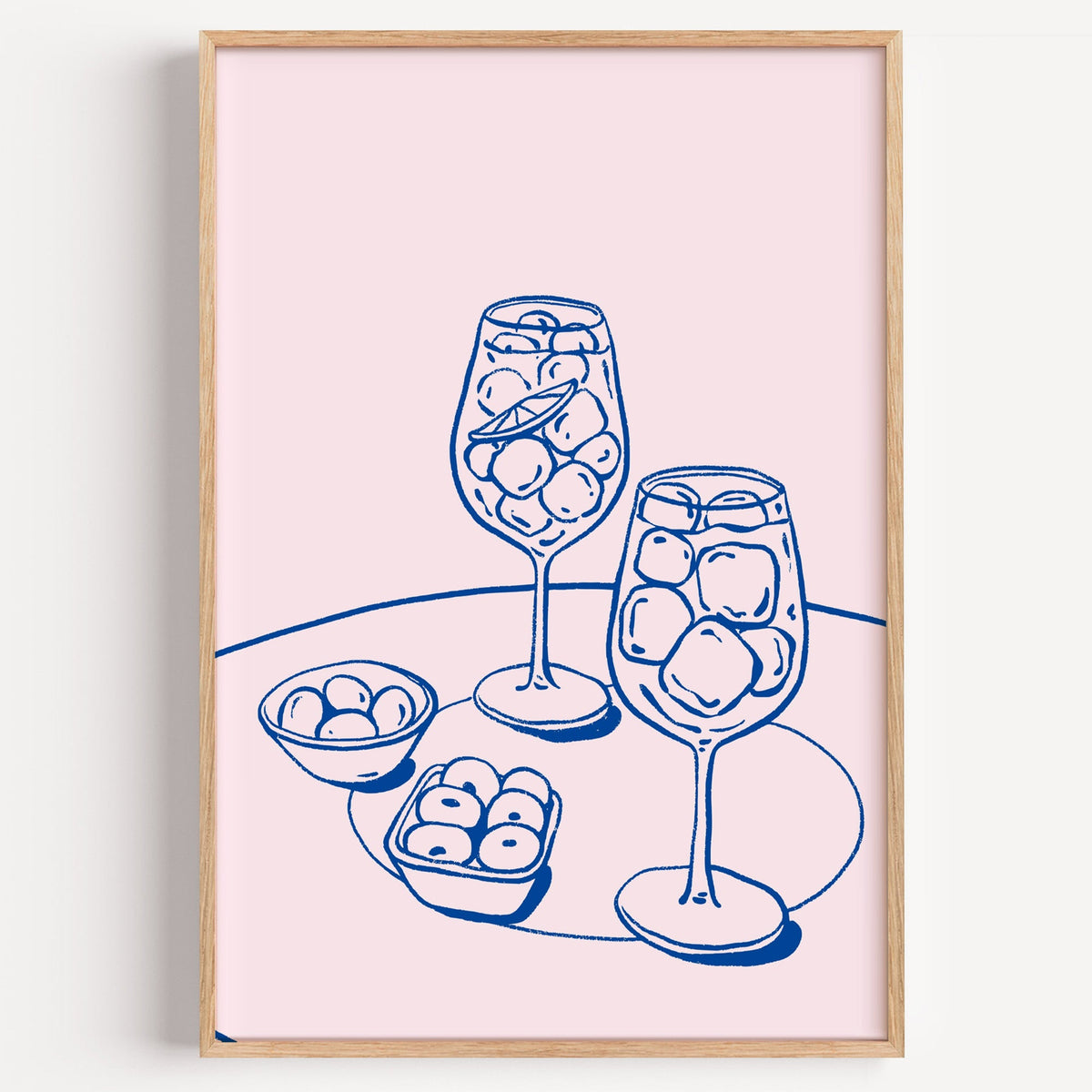 Spritz and olives aperitivo print in a light oak frame on a plain white wall