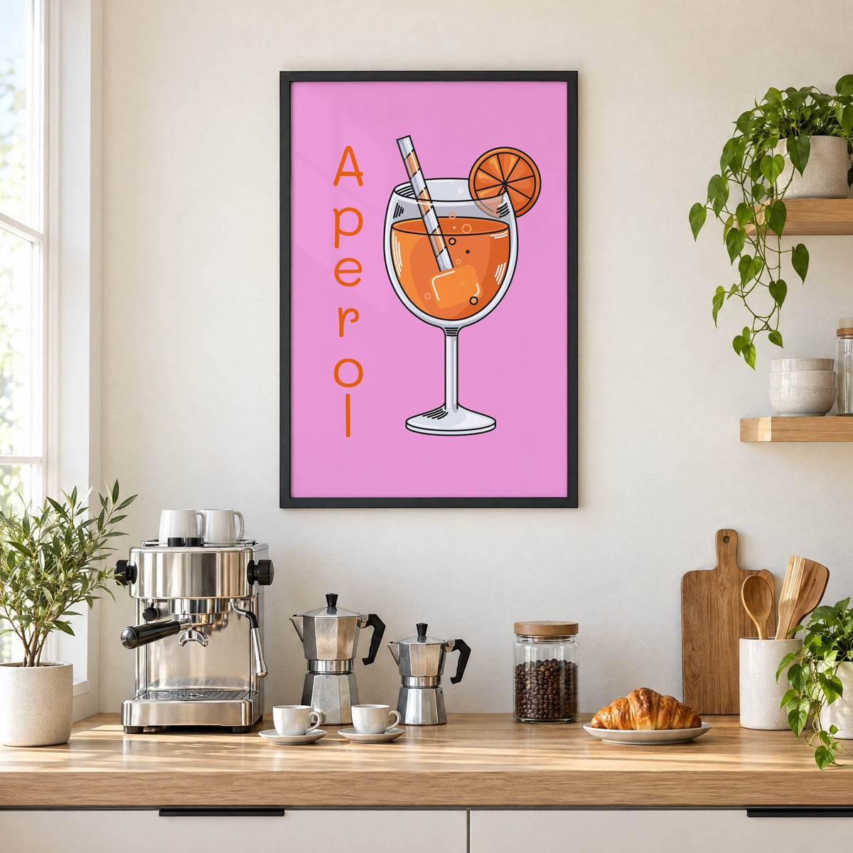 Orange spritz glass on pink print in a black frame above a home espresso bar with moka pots and espresso cups