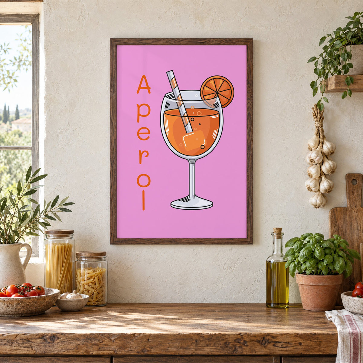 Orange spritz glass on pink print in a walnut frame above a rustic Italian pantry counter with pasta jars, garlic and tomatoes