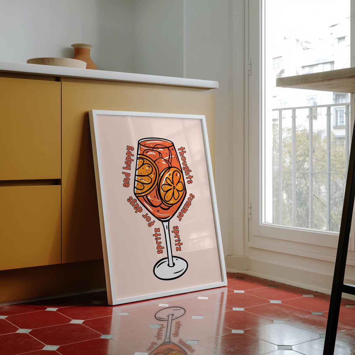 Spritz glass print in a white frame against yellow cabinets on a red tiled floor