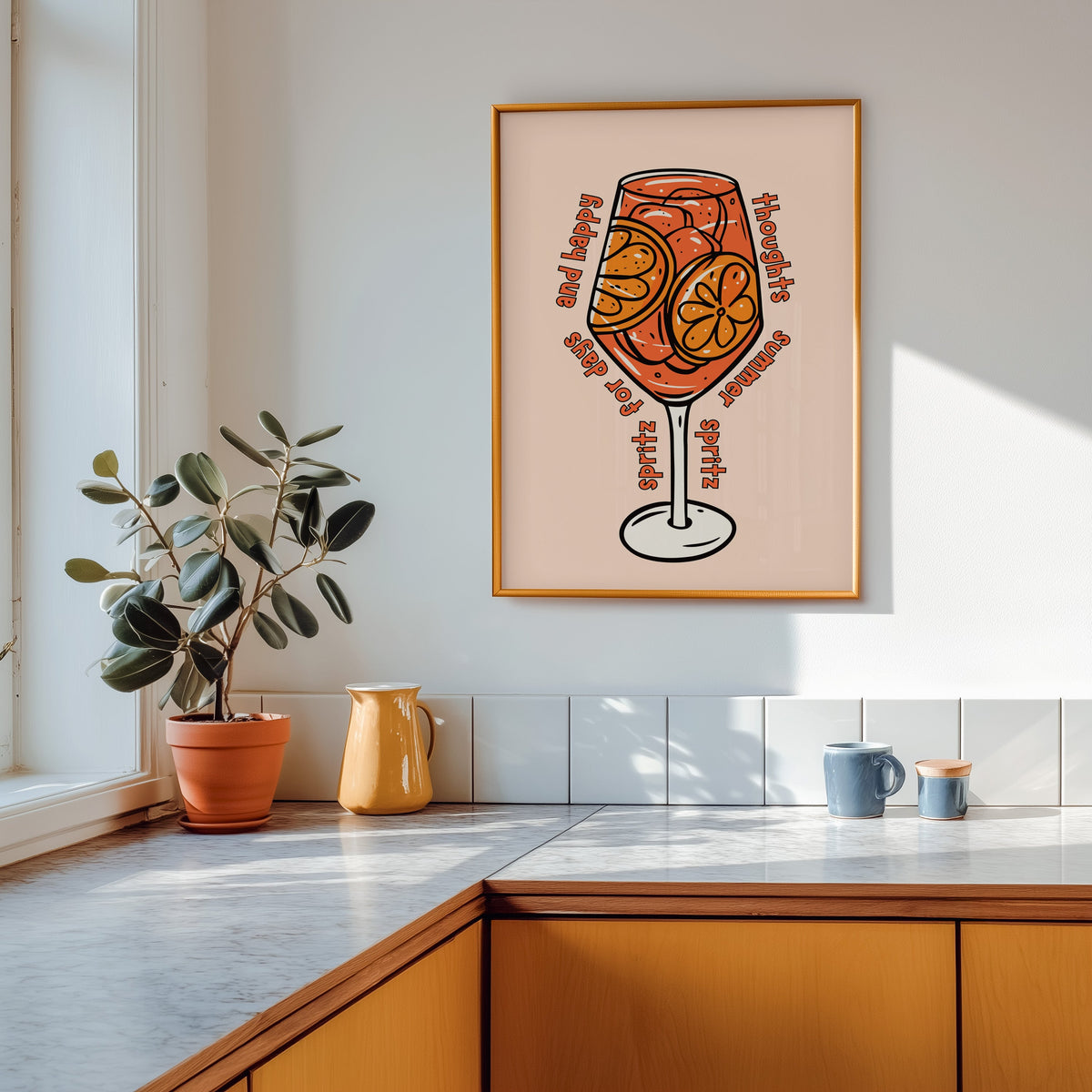 Spritz glass print in a gold frame above a marble counter with a yellow ceramic jug
