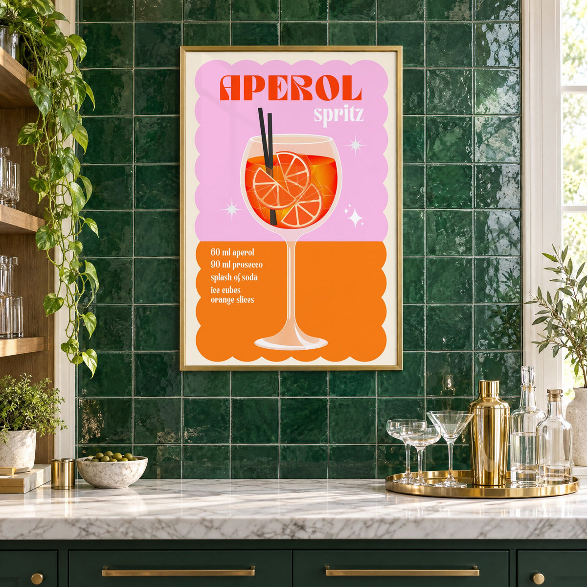 Spritz recipe pink and orange print in a brass frame on emerald green tiles above a home bar with coupe glasses