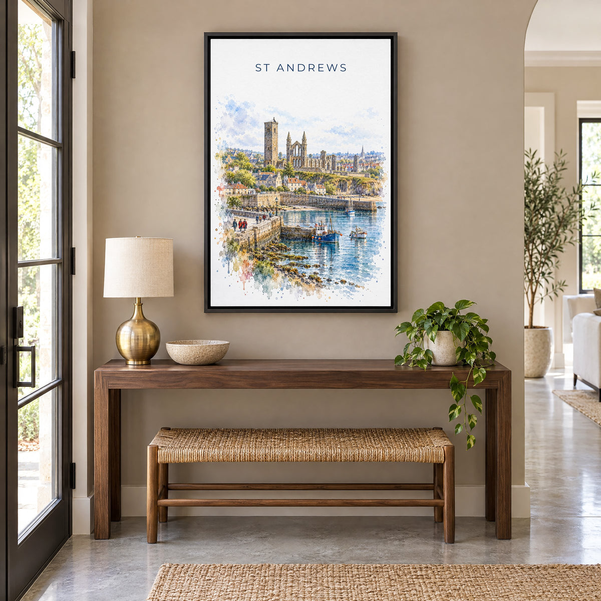 St Andrews watercolor print as a black floater canvas above a walnut console and woven bench in an entryway