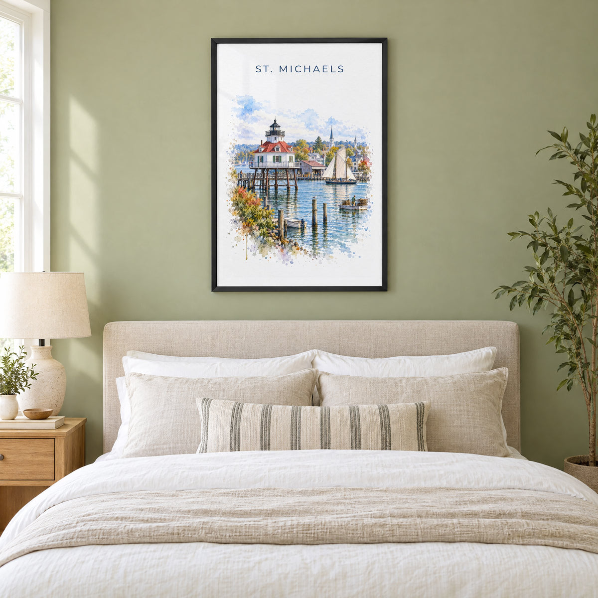 St. Michaels, Maryland watercolor print in a black frame above an upholstered headboard in a sage green bedroom