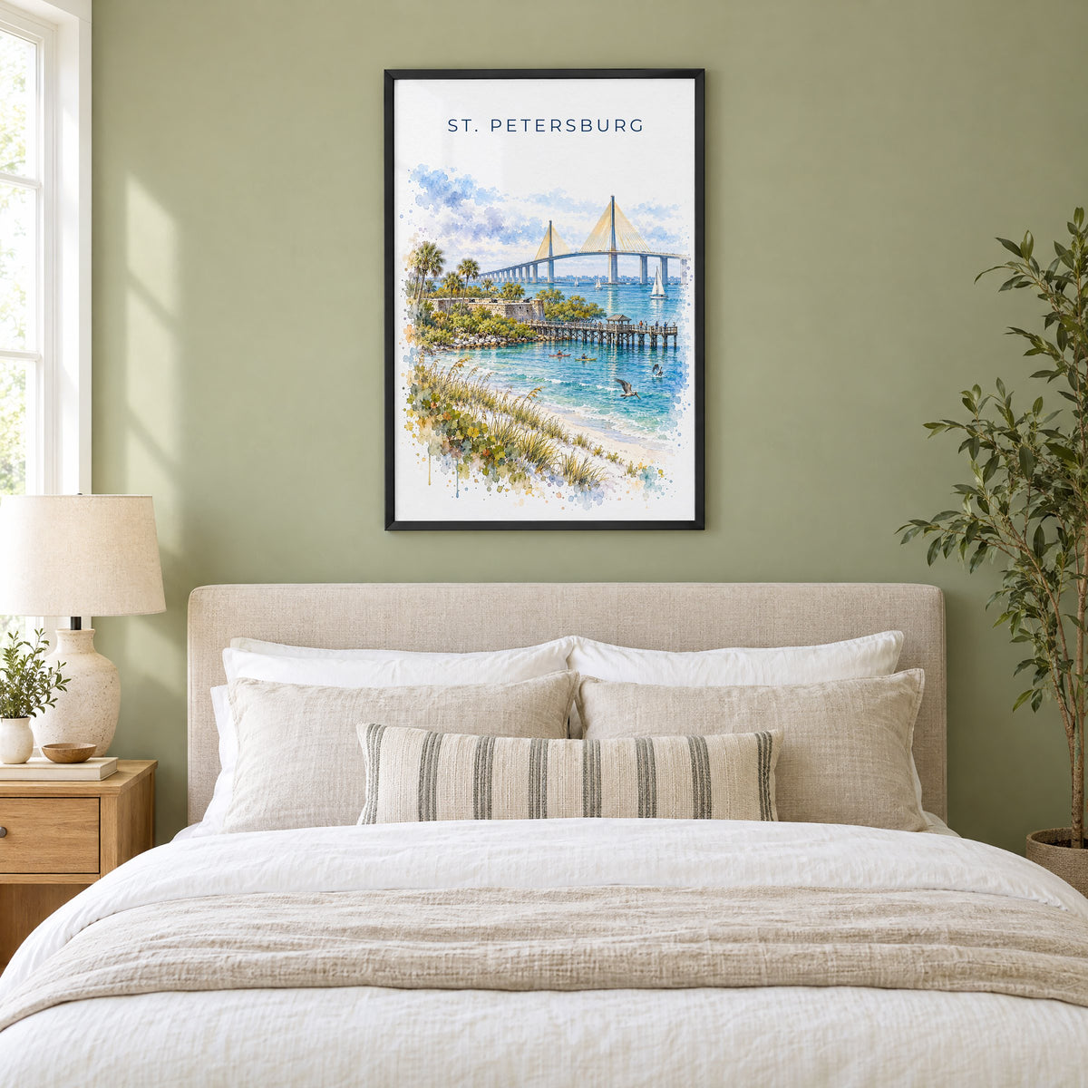 St. Petersburg, Florida watercolor print in a black frame above an upholstered headboard in a sage green bedroom