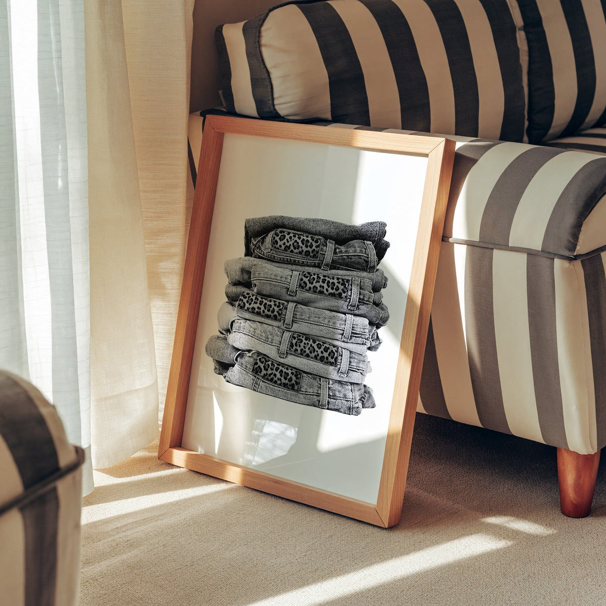 Stack of folded jeans with leopard waist patches print in a pine frame leaning against a striped armchair