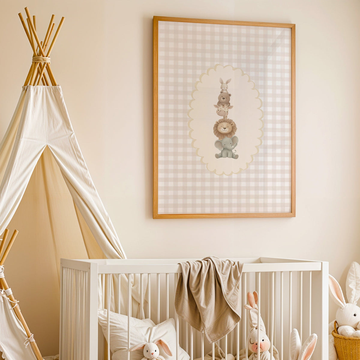 Stacked baby animals in oval on gingham nursery print in an oak frame above a white crib beside a canvas teepee