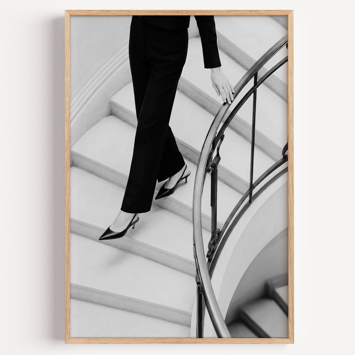 Black trousers and slingback heels on curved stairs print in a light oak frame on a plain white wall