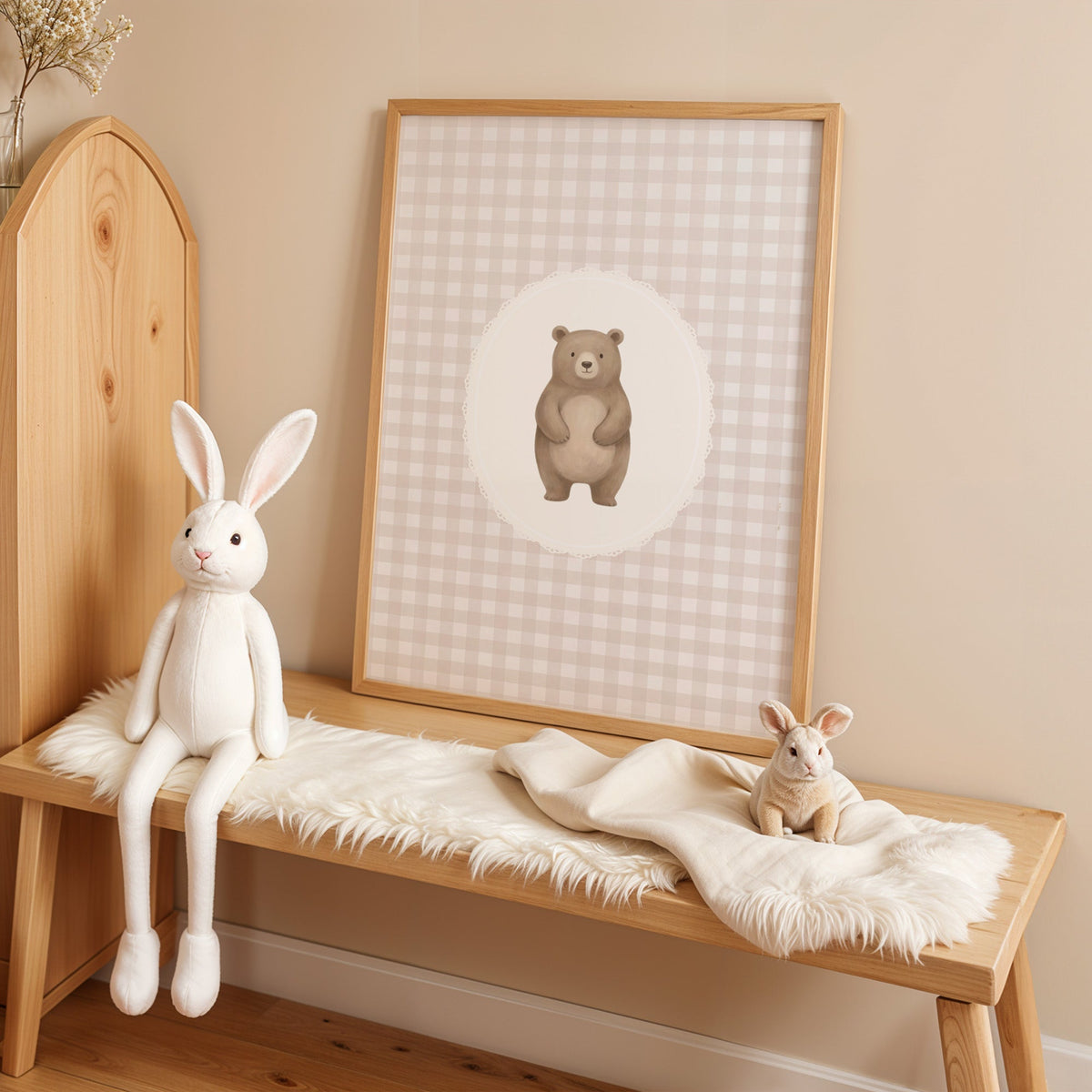 Standing bear in a lace oval on beige gingham nursery print in an oak frame on a sheepskin bench beside a white plush bunny