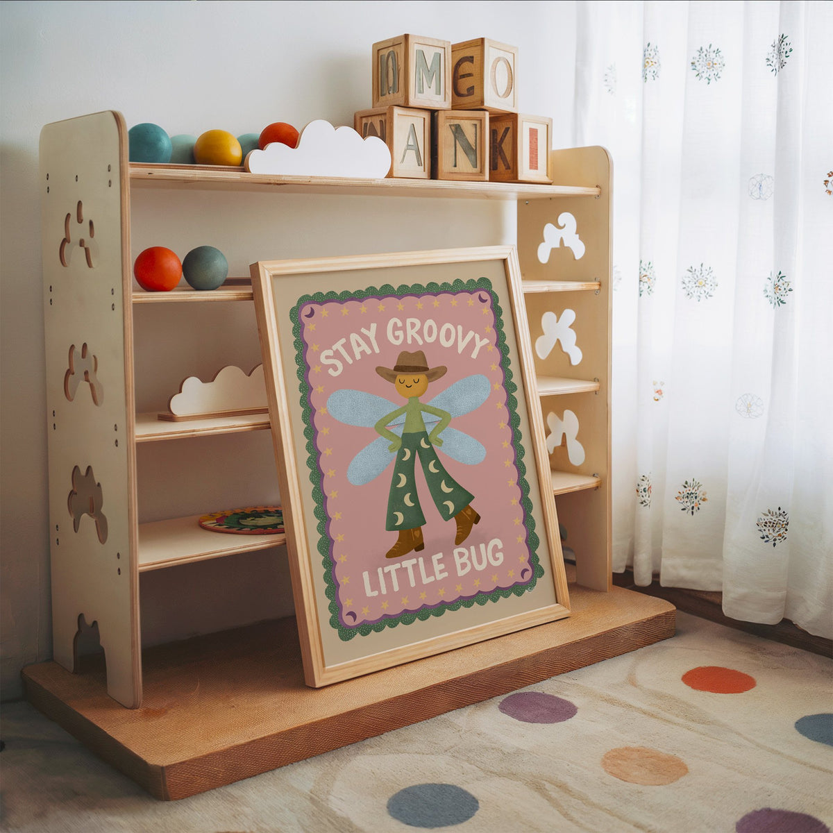Stay groovy little bug cowboy nursery print in an oak frame leaning on a toy shelf with wooden letter blocks