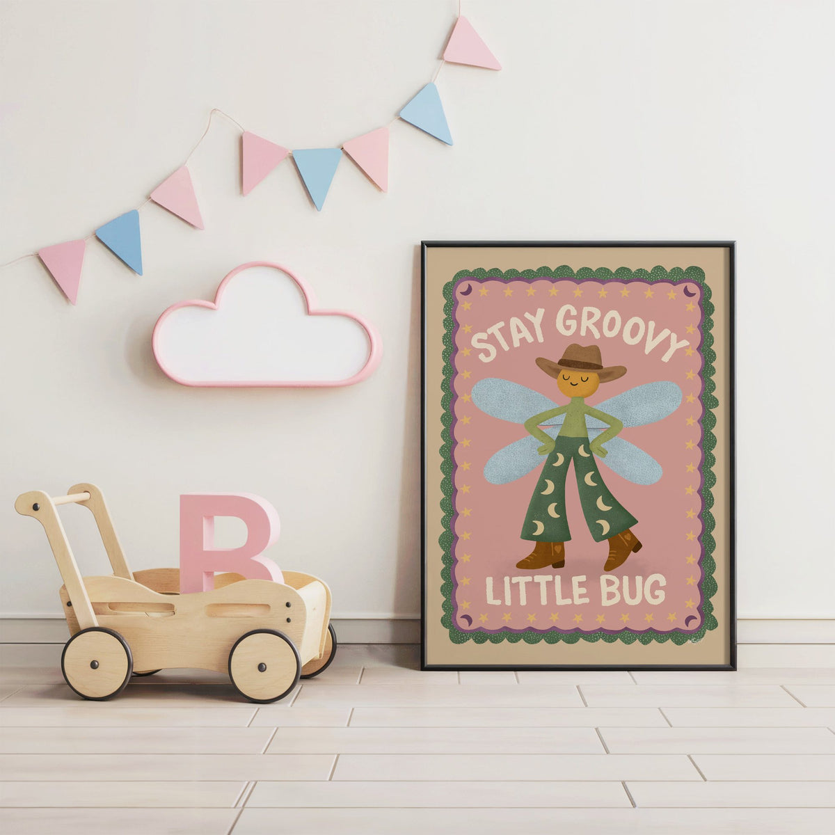Stay groovy little bug cowboy nursery print in a black frame under pastel bunting by a wooden baby walker