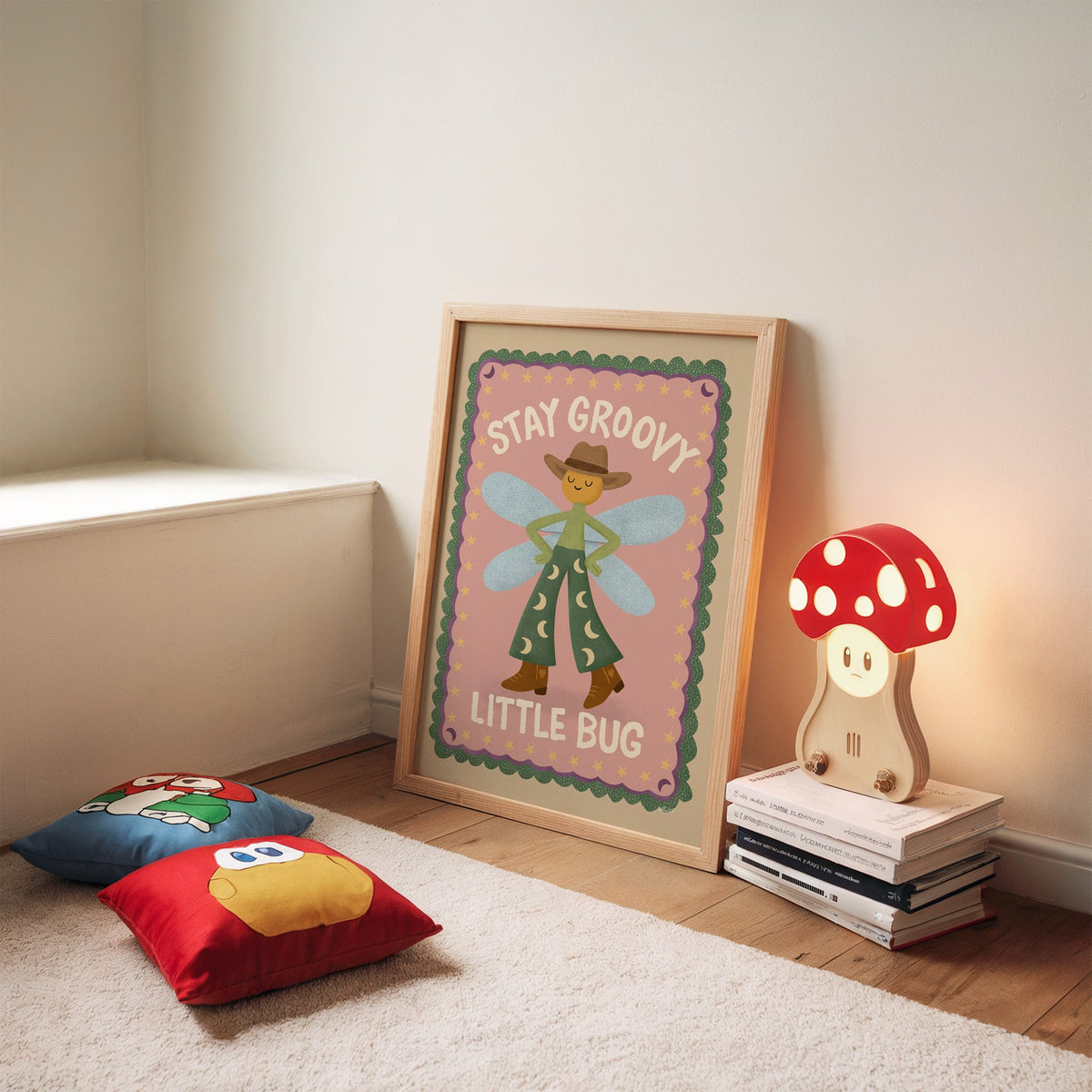 Stay groovy little bug cowboy nursery print in an oak frame leaning on a rug beside a mushroom lamp and floor cushions