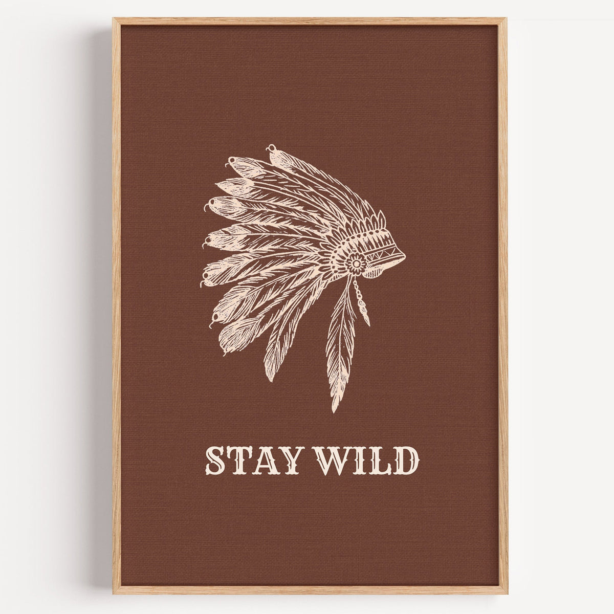 Stay Wild war bonnet print in brown in a light oak frame on a plain white wall