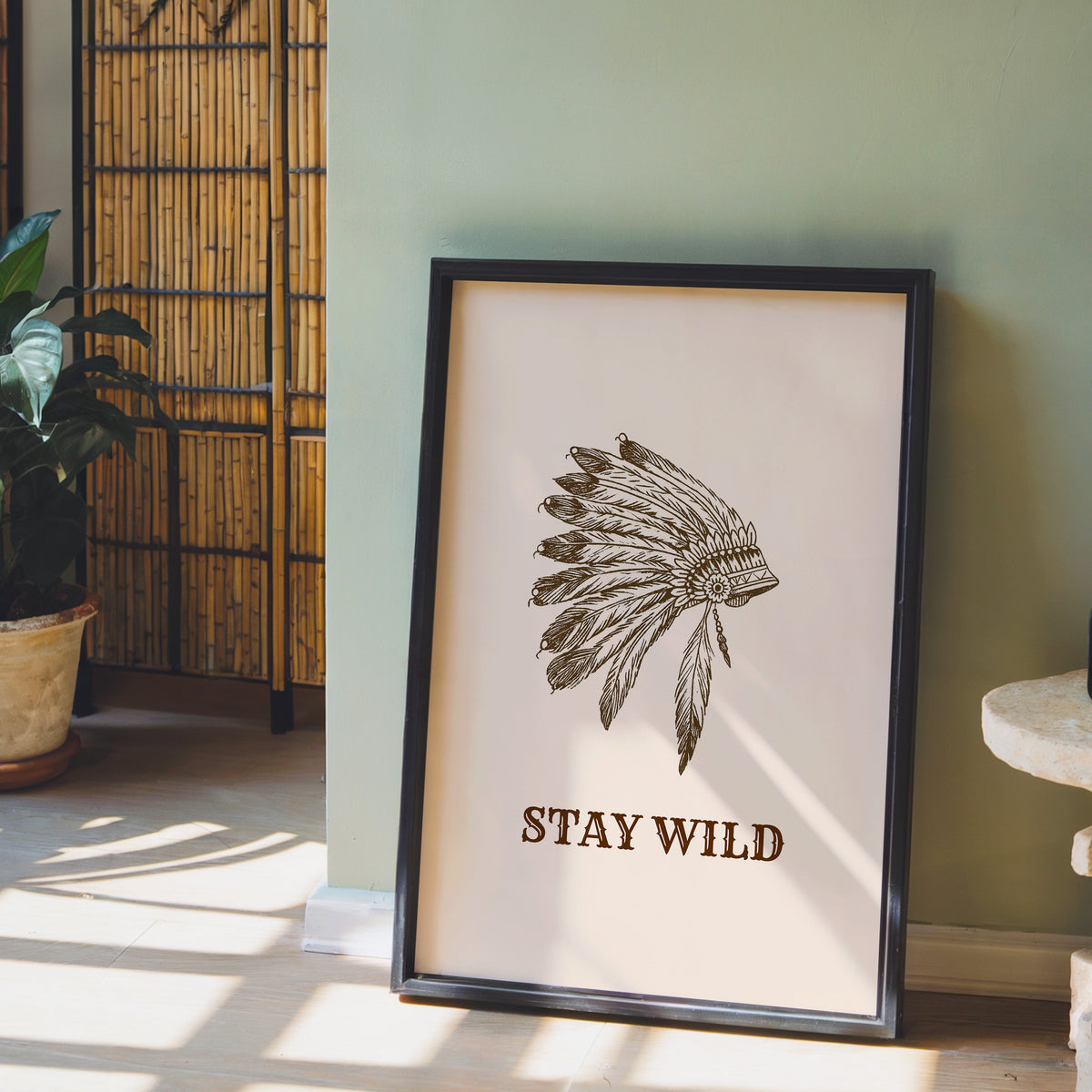 Stay Wild war bonnet cream print in a black frame leaning against a sage green wall