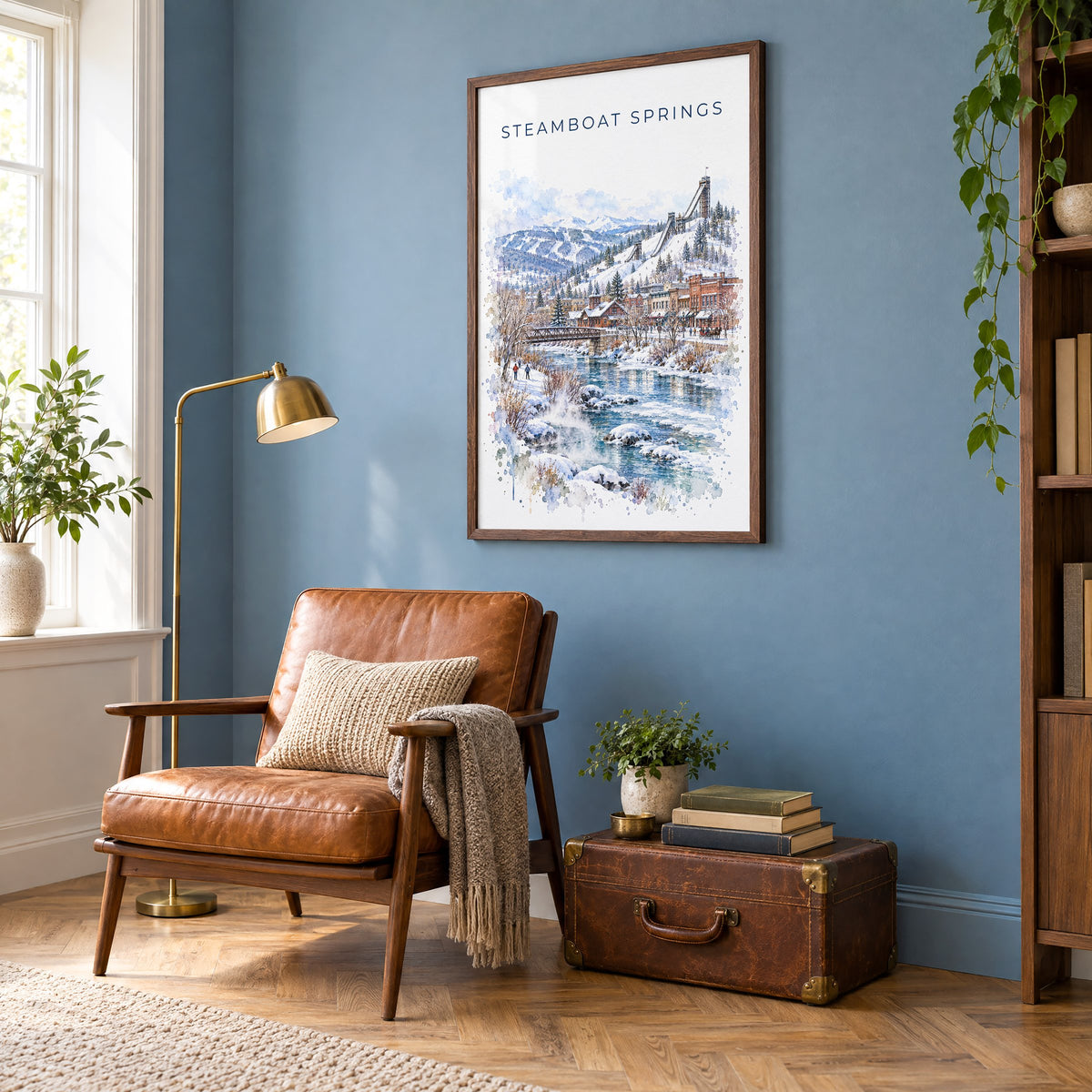 Steamboat Springs watercolor print in a walnut frame on a blue wall above a leather armchair in a reading nook