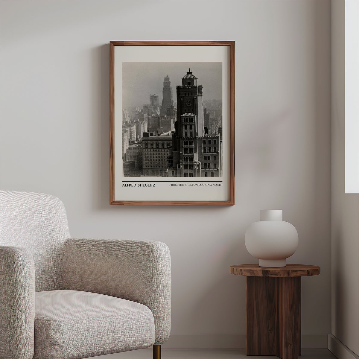 Black and white city photography print in a slim walnut frame above a bouclé armchair
