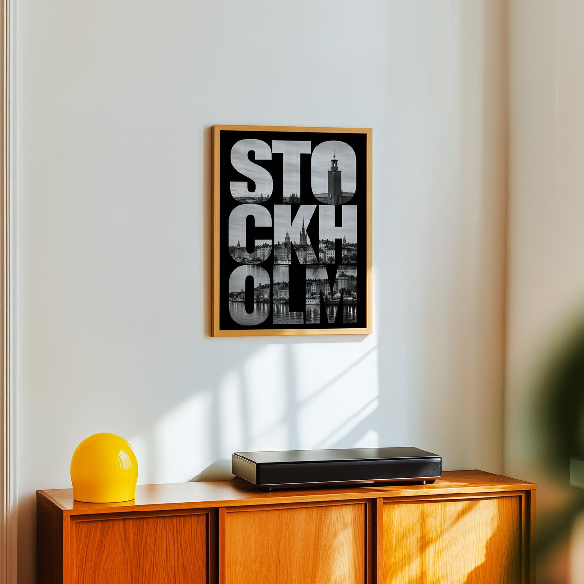 Stockholm letters filled with city photo print in an oak frame above a teak sideboard with a yellow glass lamp