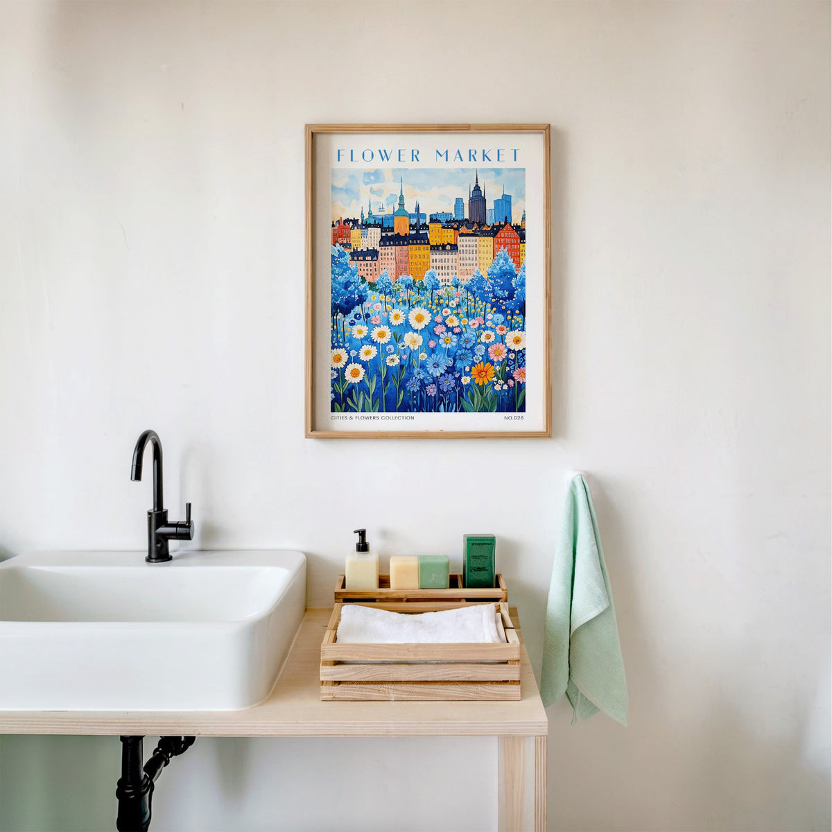 Stockholm flower market print in an oak frame above a white bathroom sink with folded towels