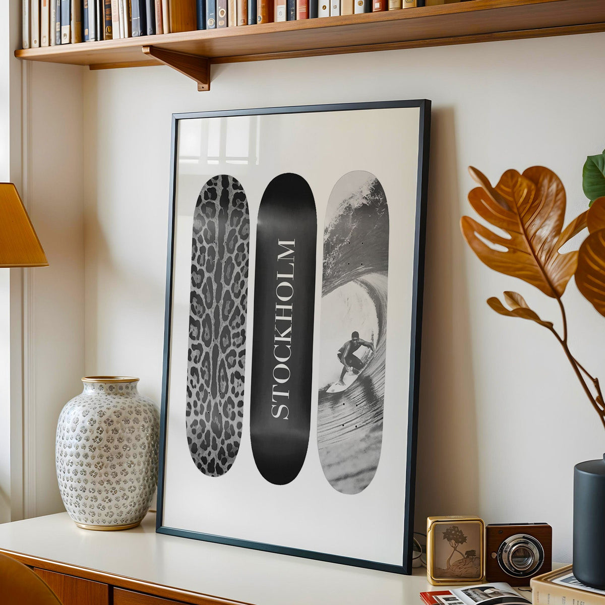 Three skateboards with leopard spots, Stockholm deck, surfer in a black frame on a console under a bookshelf
