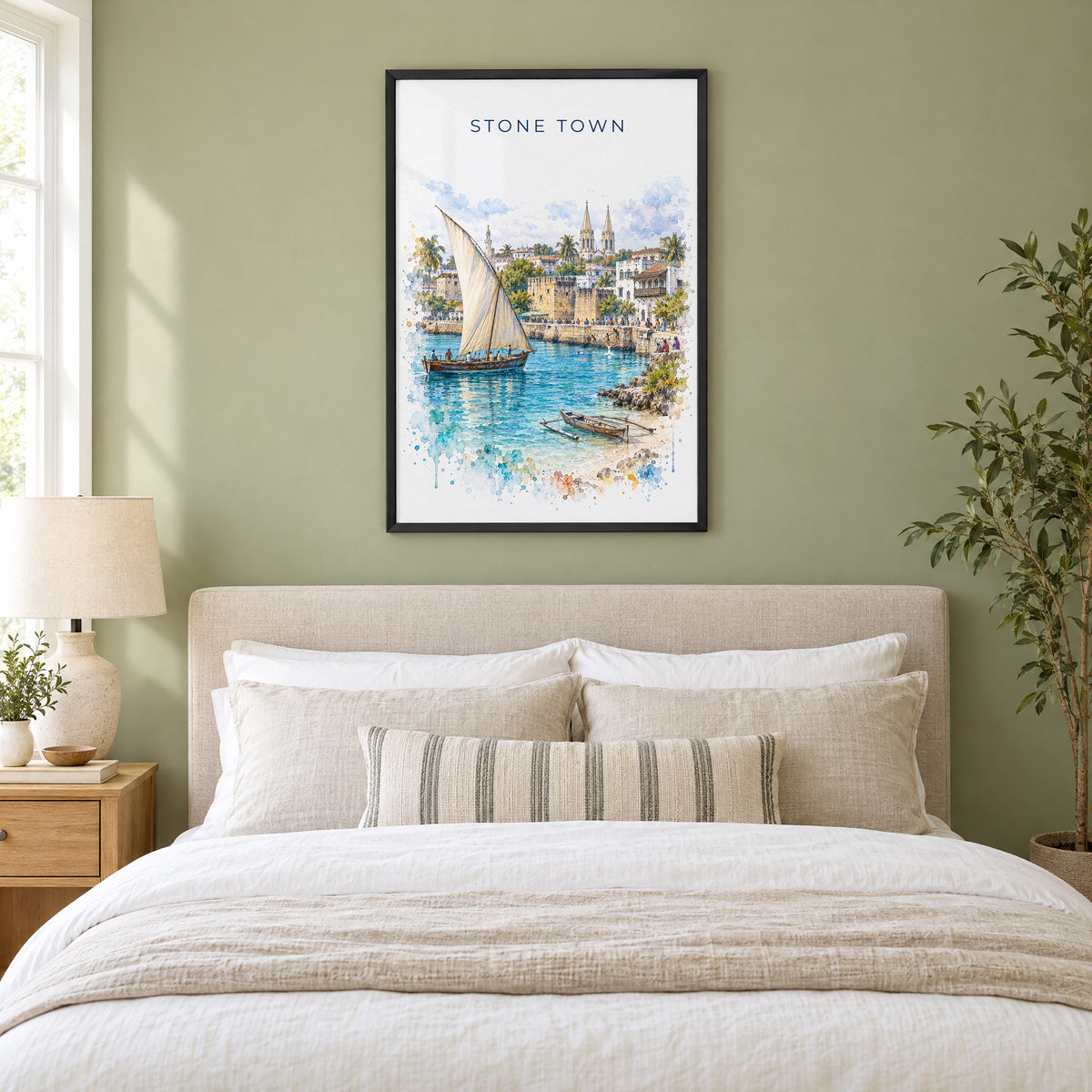 Stone Town watercolor print in a black frame above an upholstered headboard in a sage green bedroom