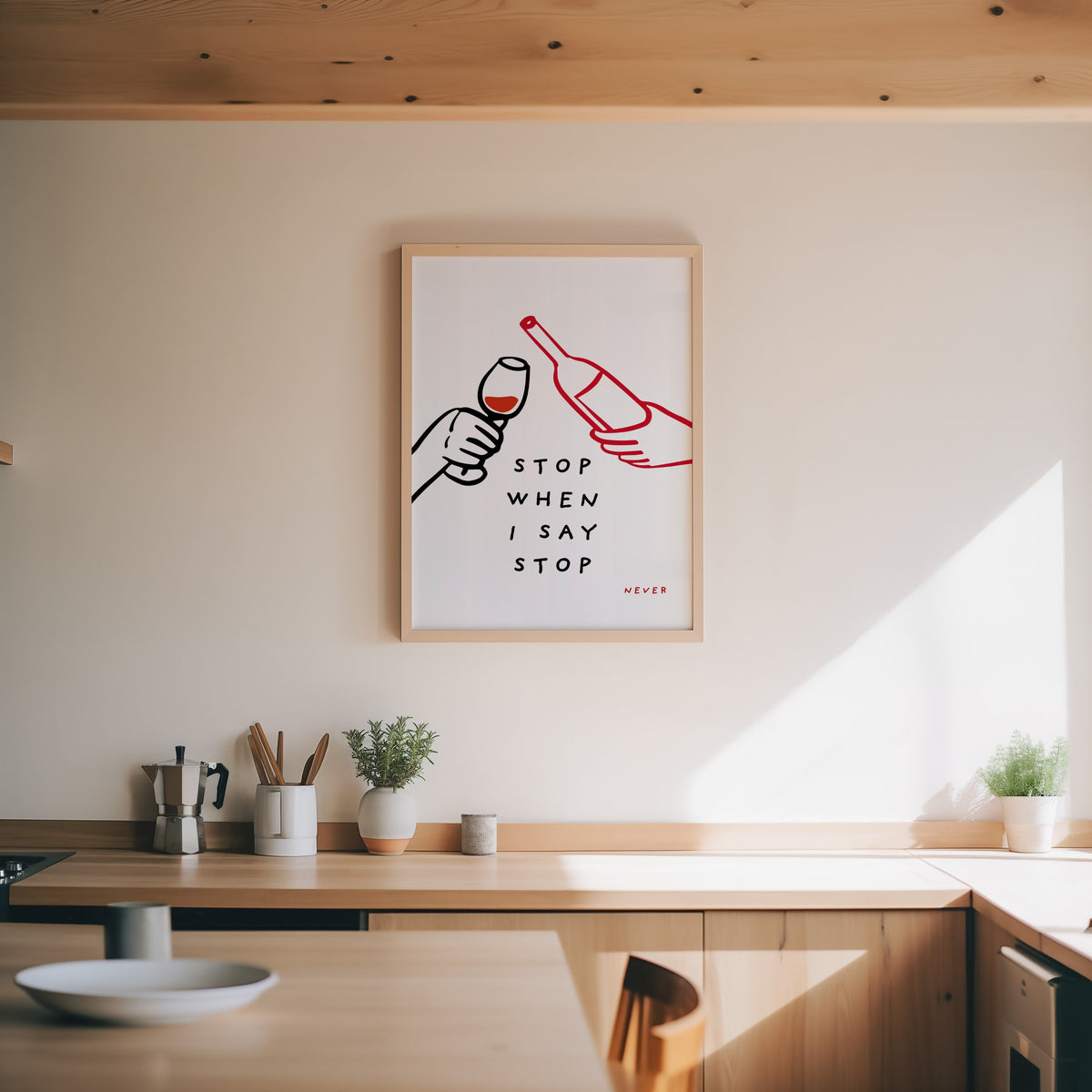 Stop When I Say Stop print in an oak frame above a wood counter with a moka pot and herbs