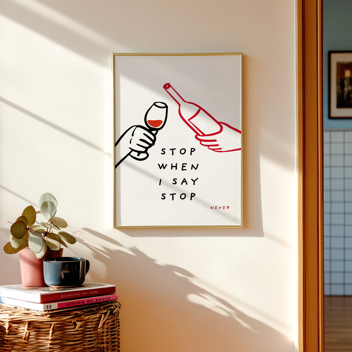 Stop When I Say Stop print shown in a gold frame above a basket of books and a pilea plant