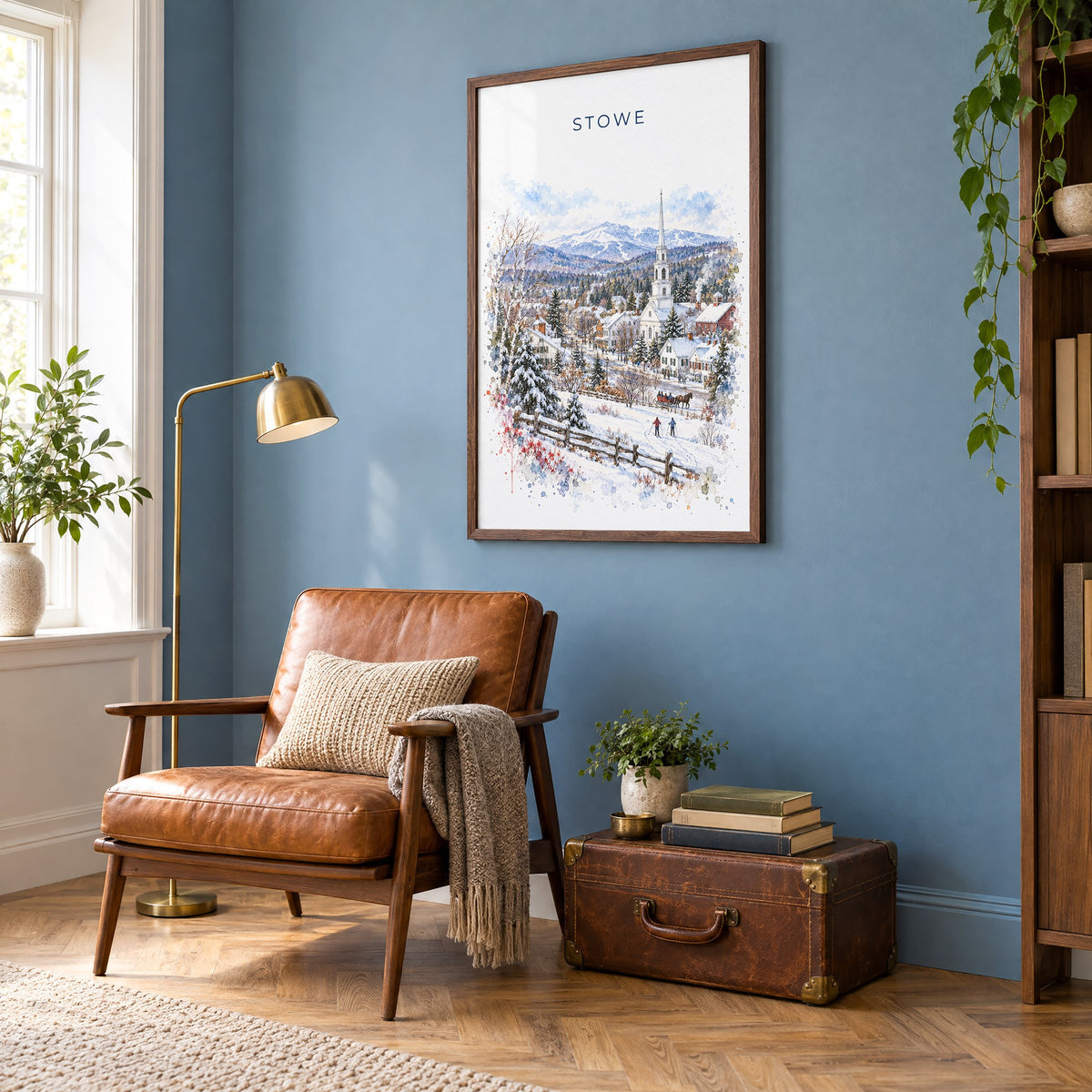 Stowe, Vermont watercolor print in a walnut frame on a blue wall above a leather armchair in a reading nook