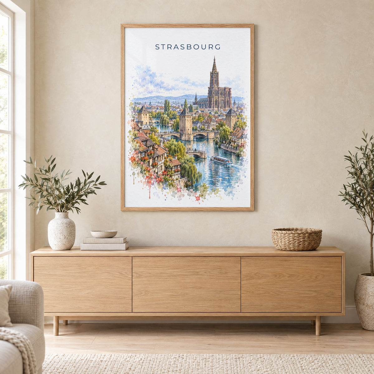 Strasbourg watercolor print in an oak frame above a light wood sideboard in a Scandinavian living room