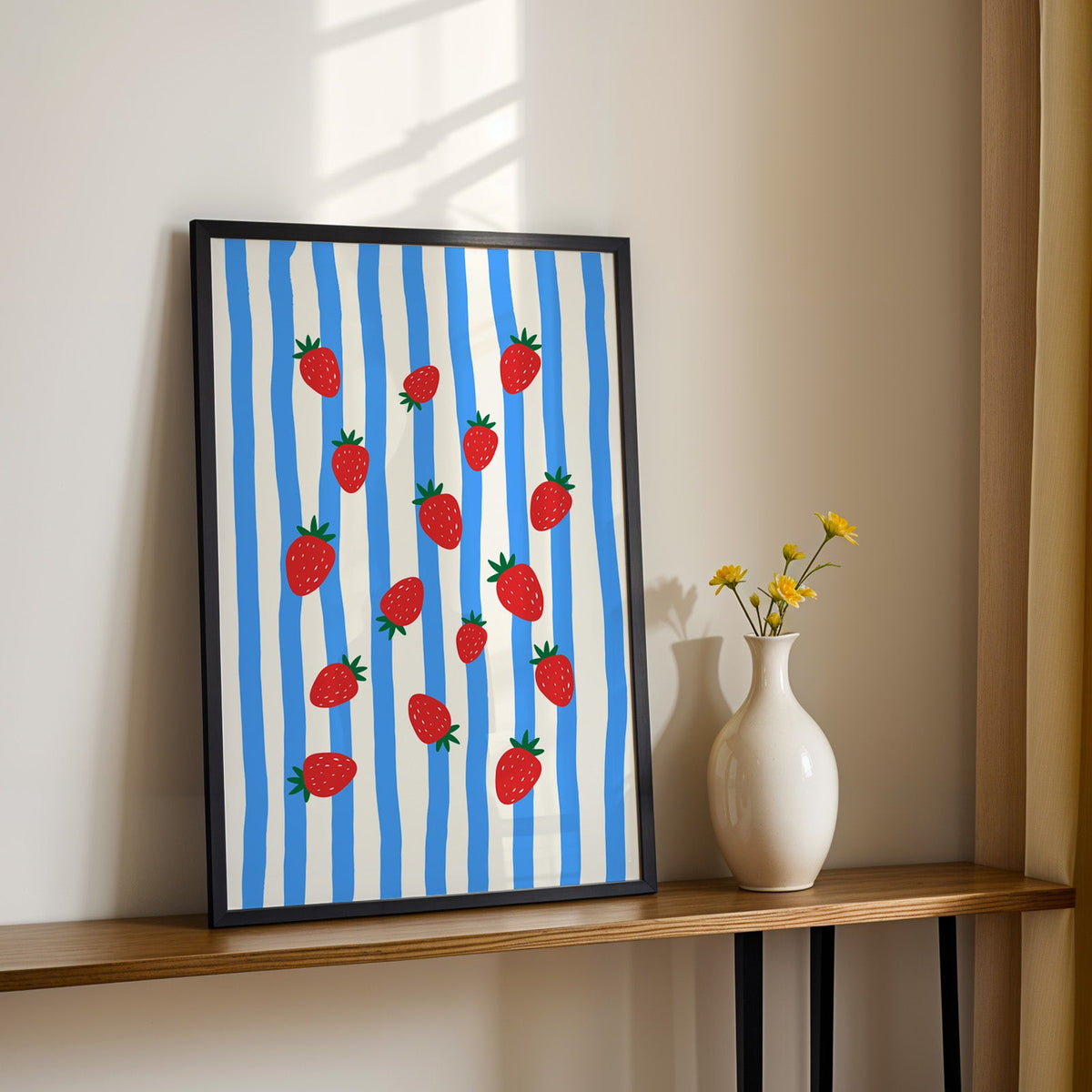 Strawberries blue stripe print in a black frame on a console table with daisies