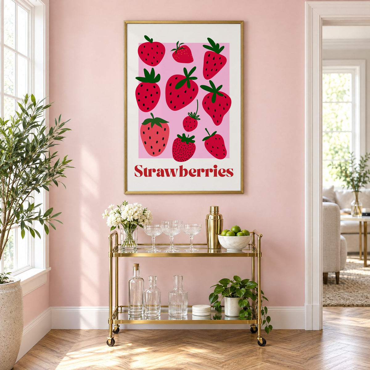 Strawberries bold serif pink panel berry print in a brass frame on a blush pink wall above a gold bar cart with glassware