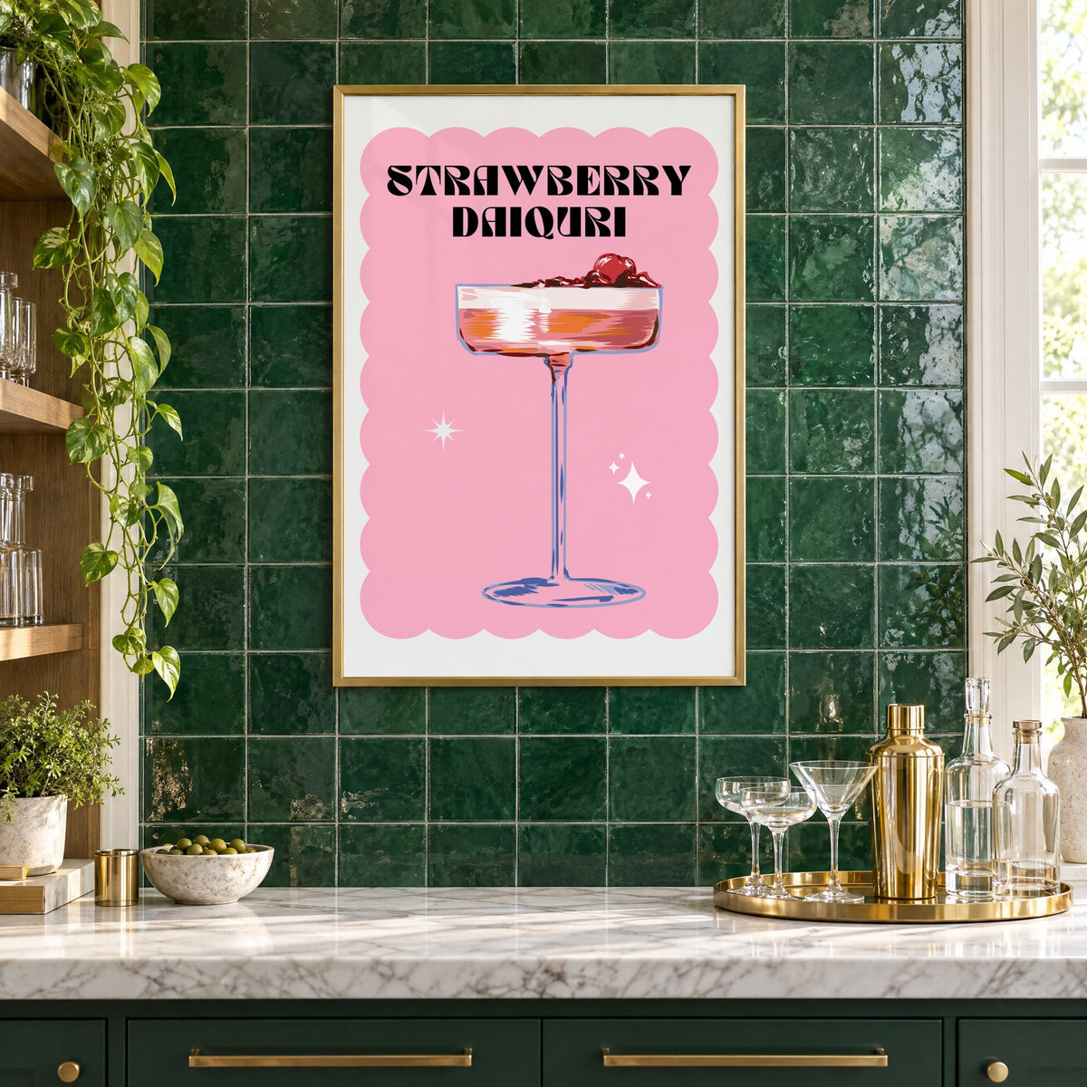 Strawberry daiquiri pink coupe print in a brass frame on emerald green tiles above a home bar with coupe glasses